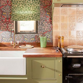 kitchen with pink patterned wallpaper green pattered blinds and pink patterned tiles and green cabinetry