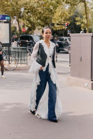 Showgoer wearing a lace bohemian dress over jeans at Paris Fashion Week.