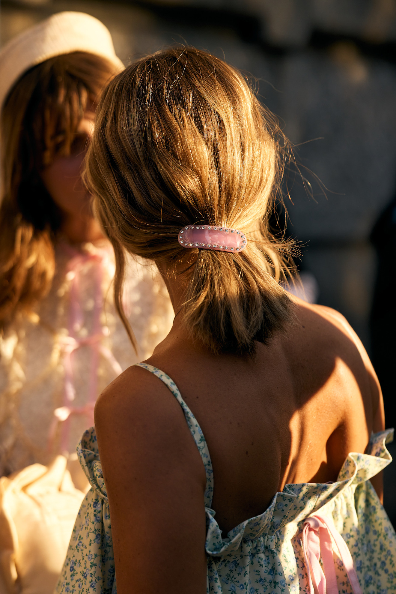 a white woman with a pink hair clip in her blonde ponytail from the back