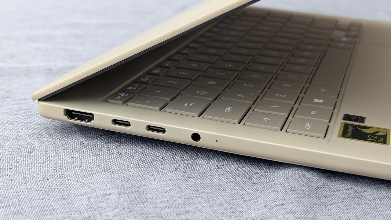 Close-up of left Zenbook A14 edge showing HDMI, USB‑C ports, audio jack, and Snapdragon X2 Elite sticker near the keyboard.