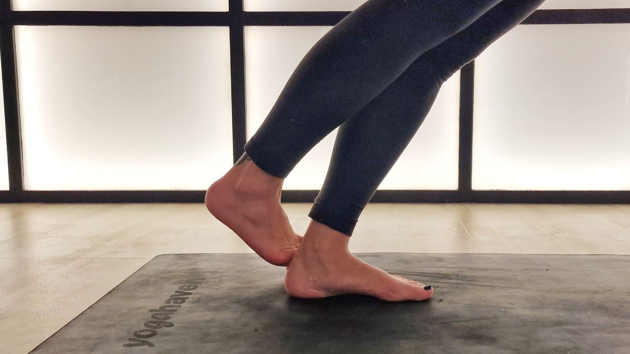 Close up of woman in downward dog variation with right foot behind left heel