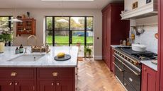 cherry red kitchen with vintage style oven and a copper tap sink built in the kitchen island