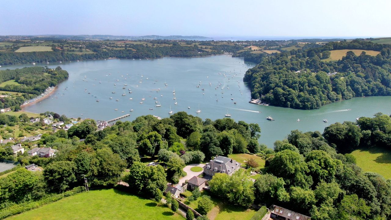 A view from above of the home with the sea in the background with boats on it