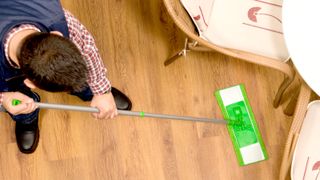 Top down shot of green mop on wooden laminate floor