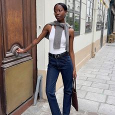 @sylviemus_ wears indigo straight jeans, a white tank top, grey jumper and black mules