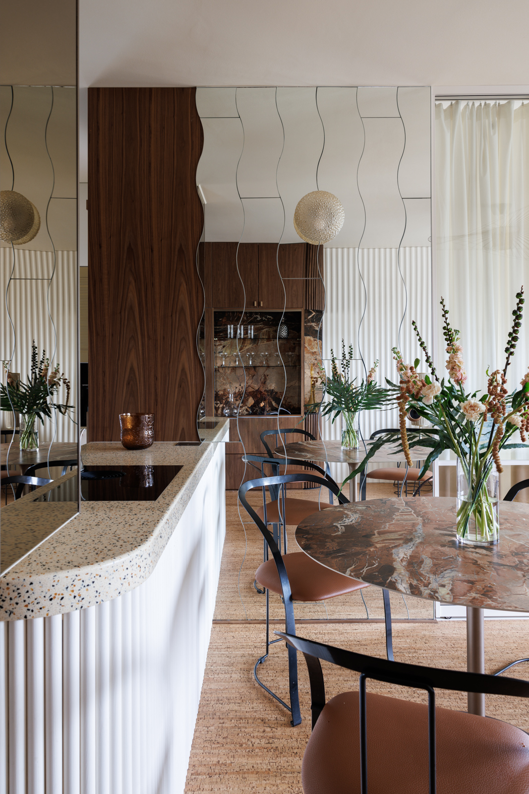 A glamorous suite fitted with reflective mirrored walls, wavy detailing, brass accents, dark woods, and plush leather and textiles.