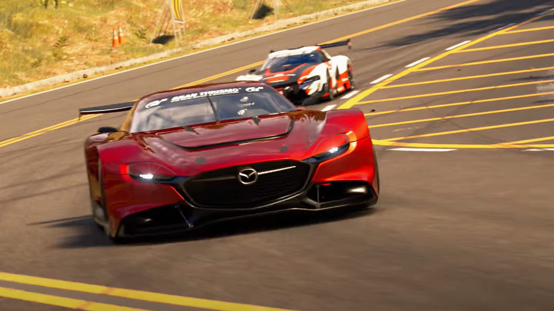 Gran Turismo 7 gameplay showing a red Mazda driving round a track in front of another car
