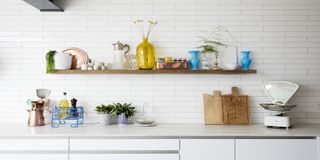 White kitchen with wooden floating shelf and various kitchen accessories