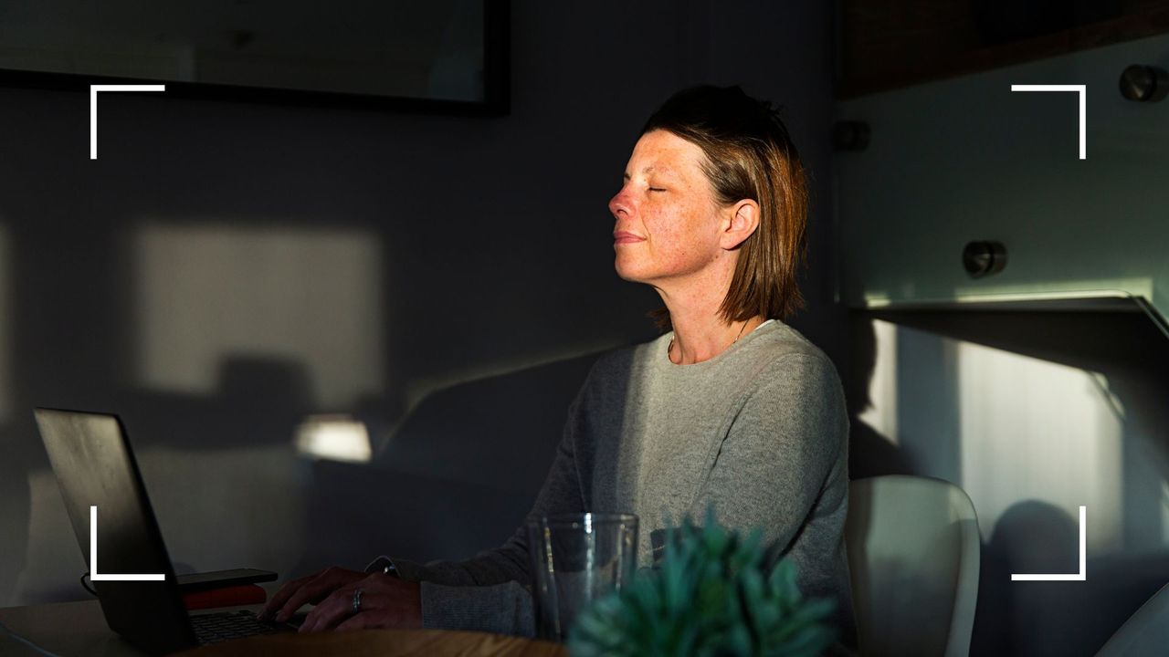 Woman sitting in the last ray of sunlight of the evening at kitchen table, eyes closed, practicing Sophrology