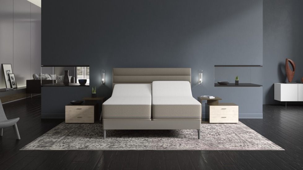 The image shows a Sleep Number Smart Bed mattress with adjustable firmness in a modern bedroom with grey walls and a grey rug 