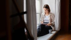 Woman reading book in corner by the window