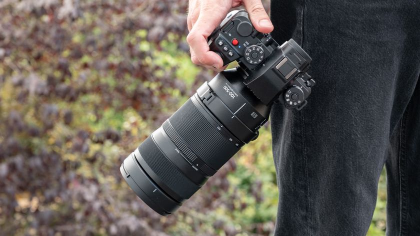 Panasonic Lumix S1II camera with a Lumix S 100-500mm f/5-7.1 lens attached held in a pair of hands outdoors