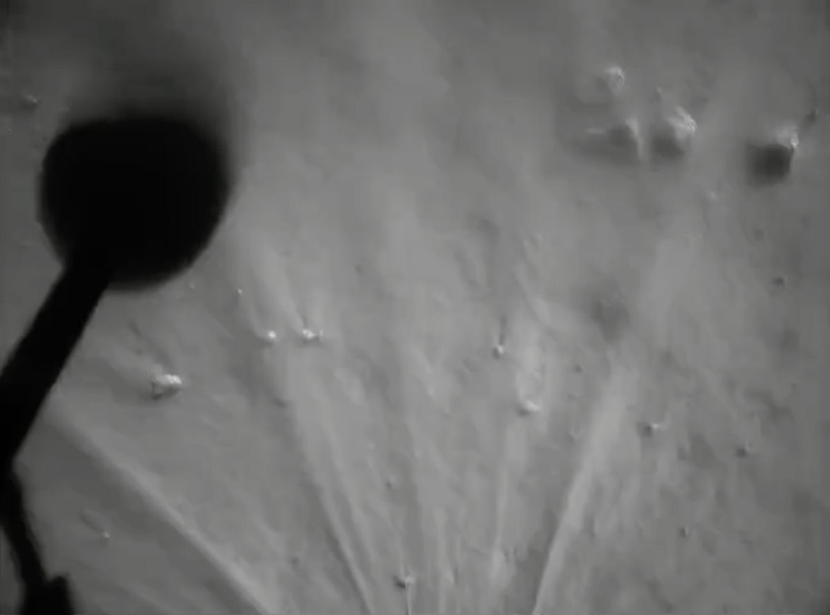 The shadow of a Chang'e 5 moon lander leg is seen in this view captured during landing. The dust plume from the final landing is also visible.