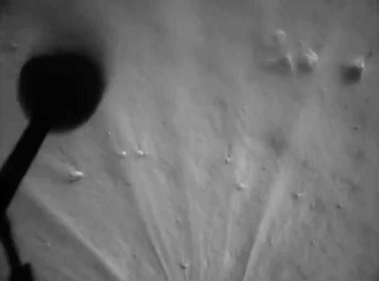 The shadow of a Chang'e 5 moon lander leg is seen in this view captured during landing. The dust plume from the final landing is also visible.