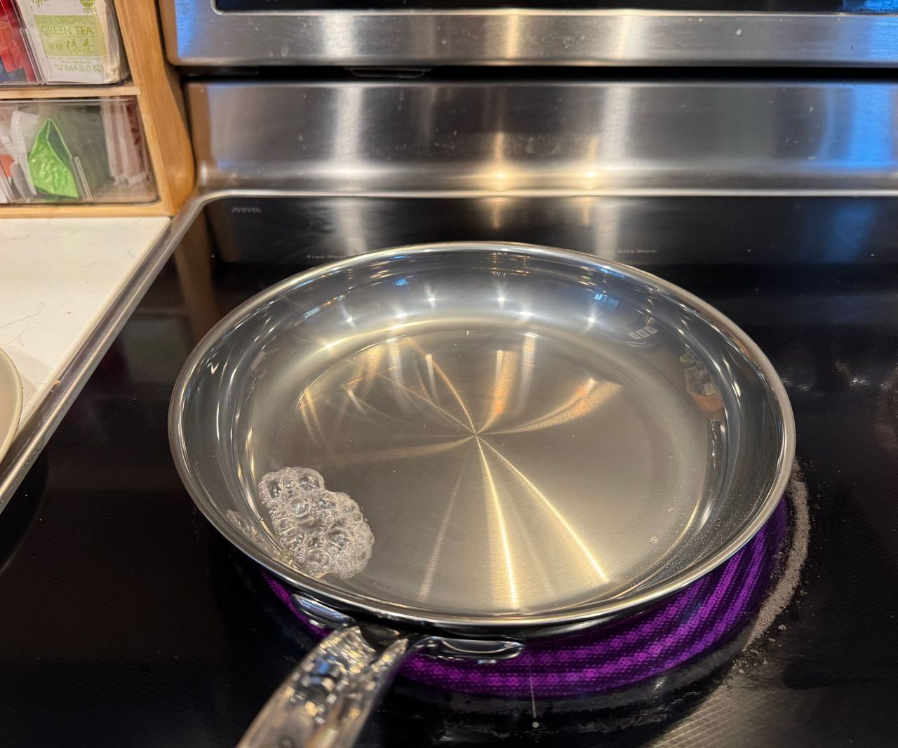 The Hestan NanoBond Skillet with waiter on the surface, on a black stovetop