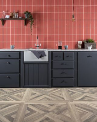 vertical terracotta orange subway metro tiles in a dark blue kitchen with Belfast sink and herringbone design floor