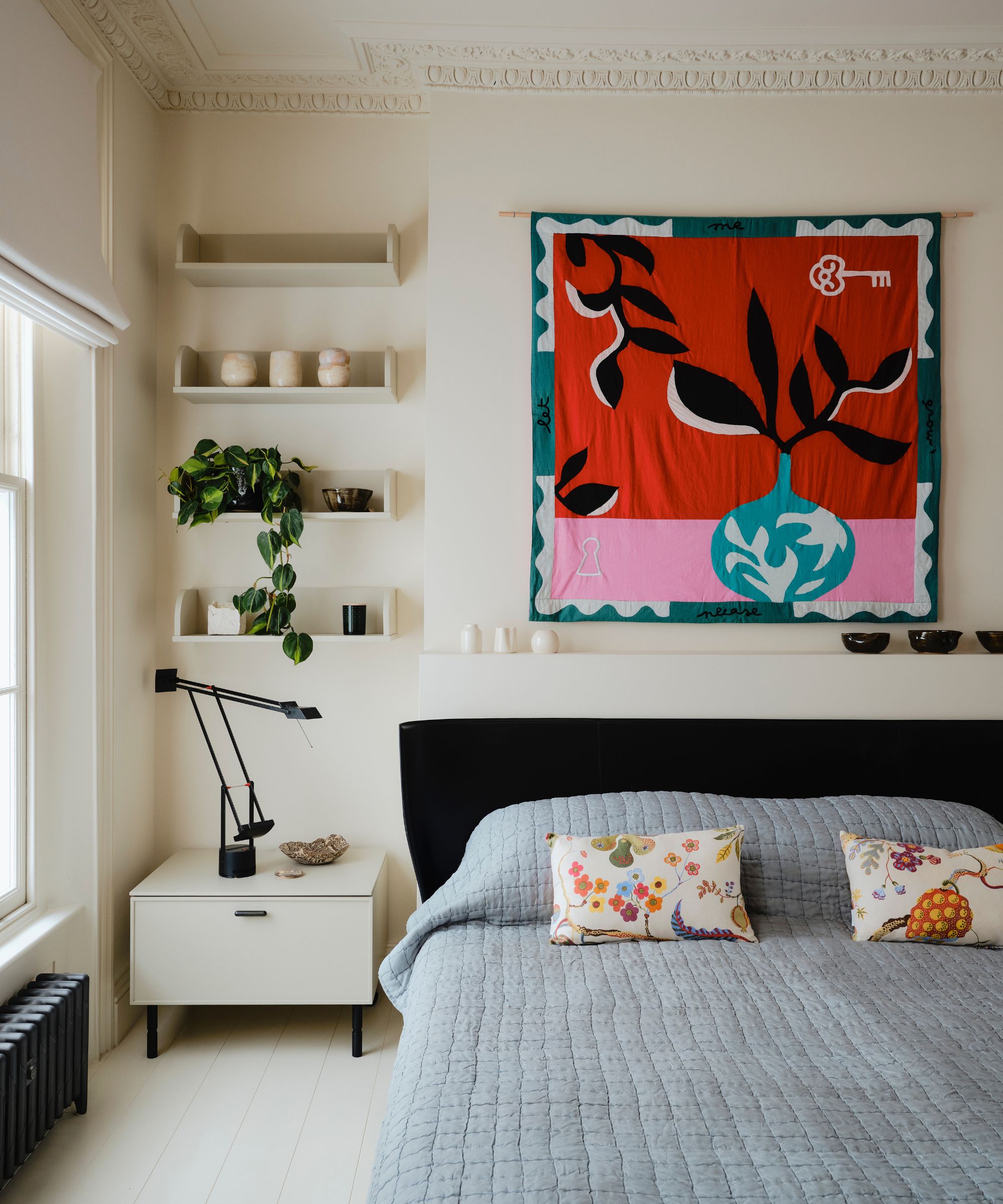Minimalist cream bedroom with shelving with house plants and statement artwork above the bed