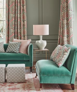 colors that go with teal, living room with sage green walls, teal couches, vintage rug, paisley print drapes in pink and grey, footstools, sculptural lamp