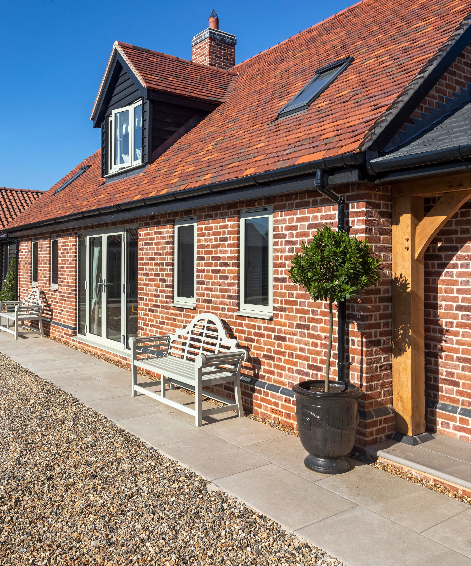House with a patio strip in front of it next to gravel