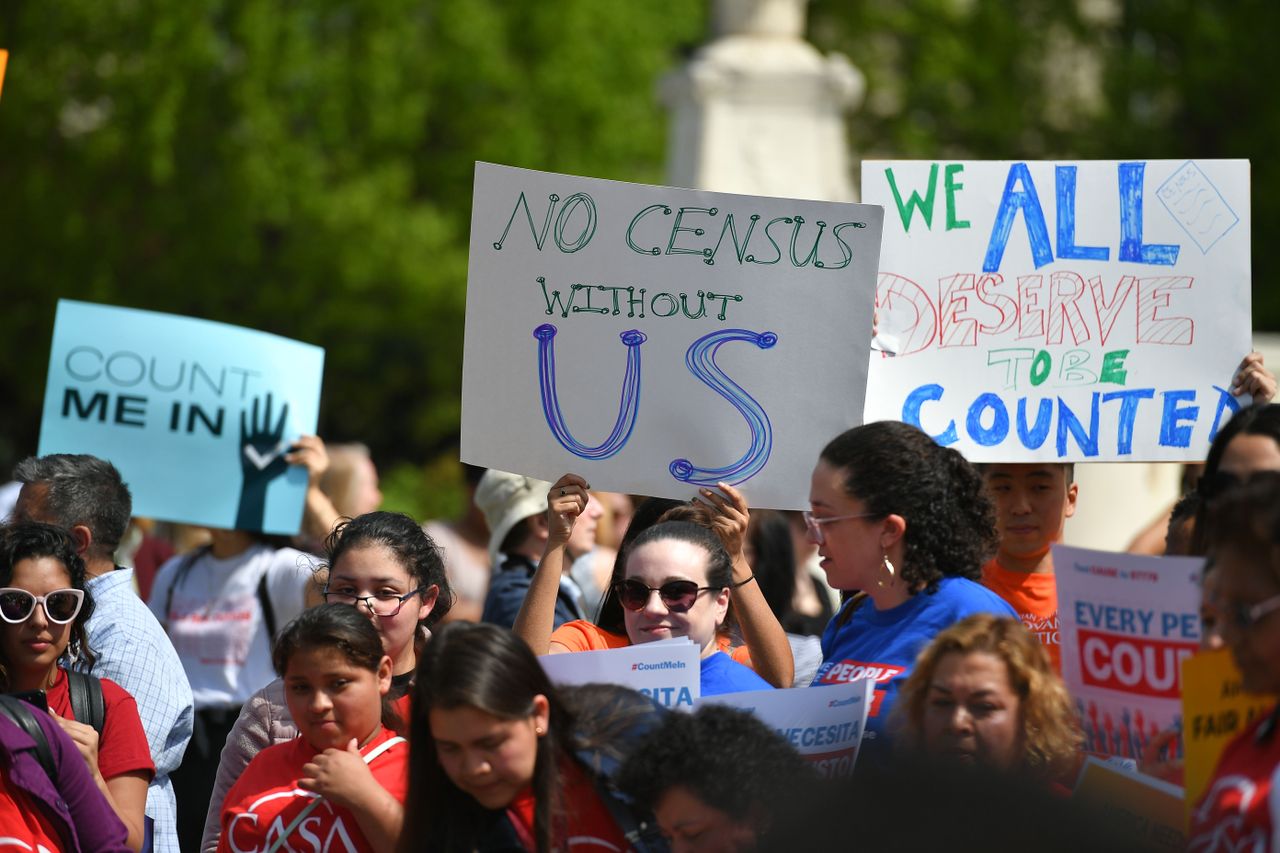 Demonstrators hold signs about the census