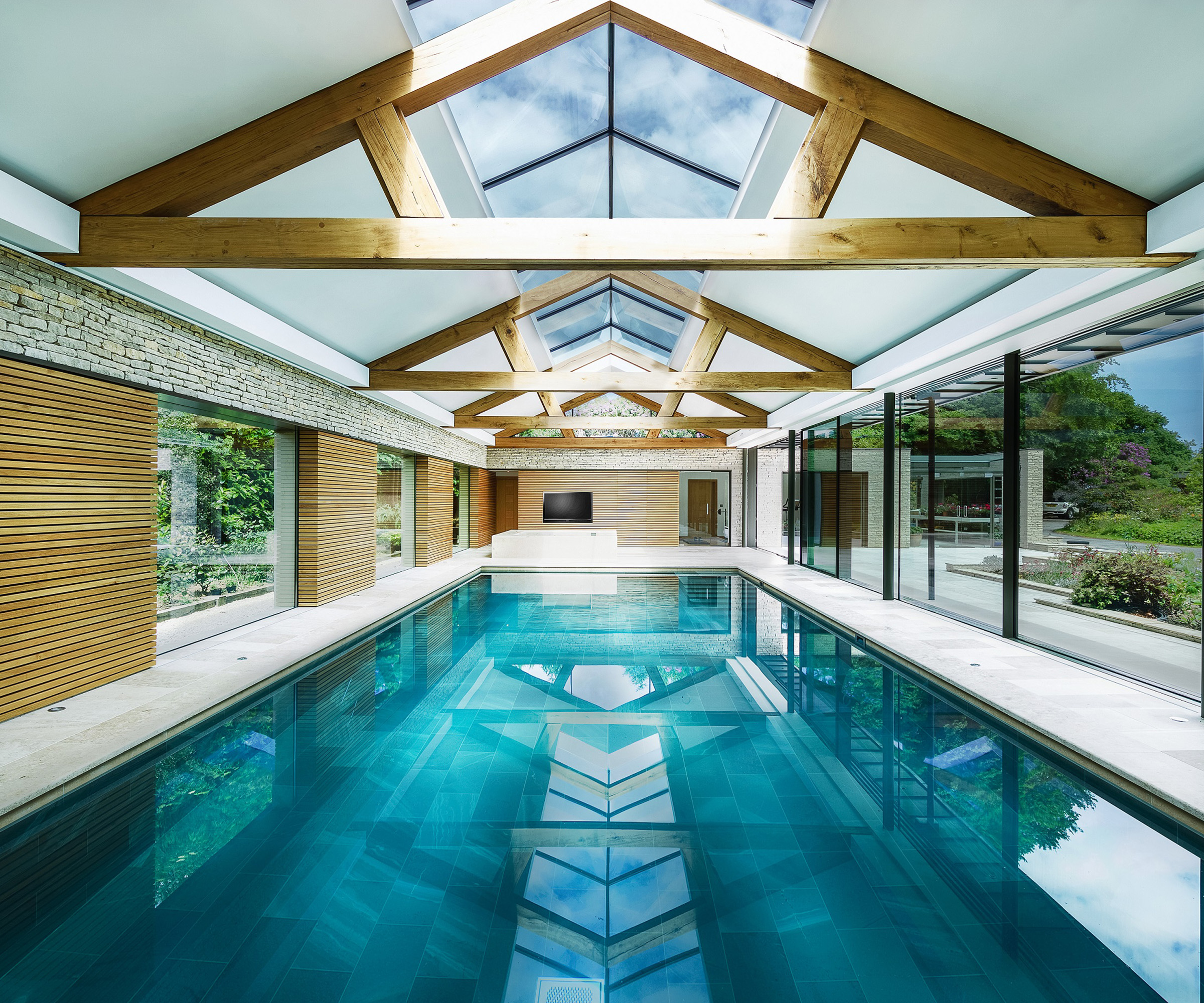 An indoor pool in specially made pool house with glass gabled roof and large bifold doors