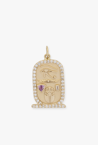 a diamond lined gold charm from Jacquie Aiche in front of a plain backdrop