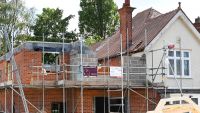 Scaffolding around a red brick extension being built to the side of a house