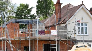 Scaffolding around a red brick extension being built to the side of a house