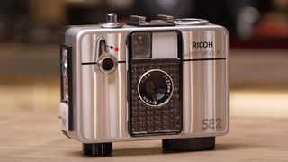 A Ricoh Auto Half film camera sitting on a table