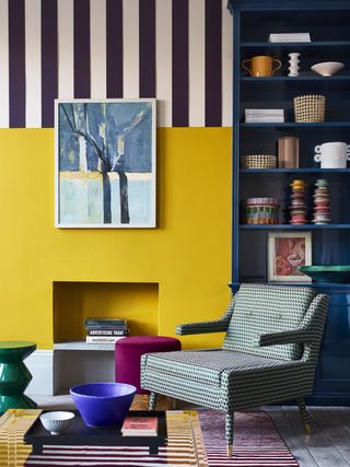 A living room decorated in bright colors with a yellow fireplace and striped walls