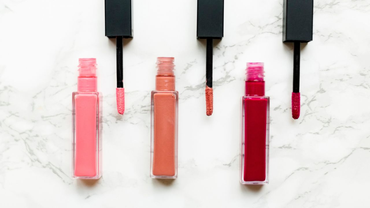 Trio of open lip glosses on a white marble background