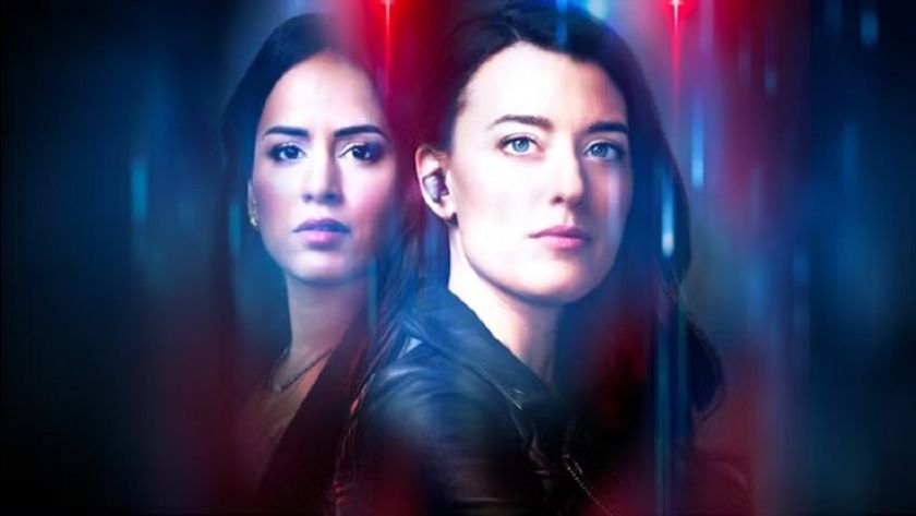 A red and blue police-inspired color motif surrounds a medium shot of Sunny, played by Agam Darshi, beside detective Tess Avery, played by Dolly Lewis in a press image for &quot;Sight Unseen&quot; season 2.