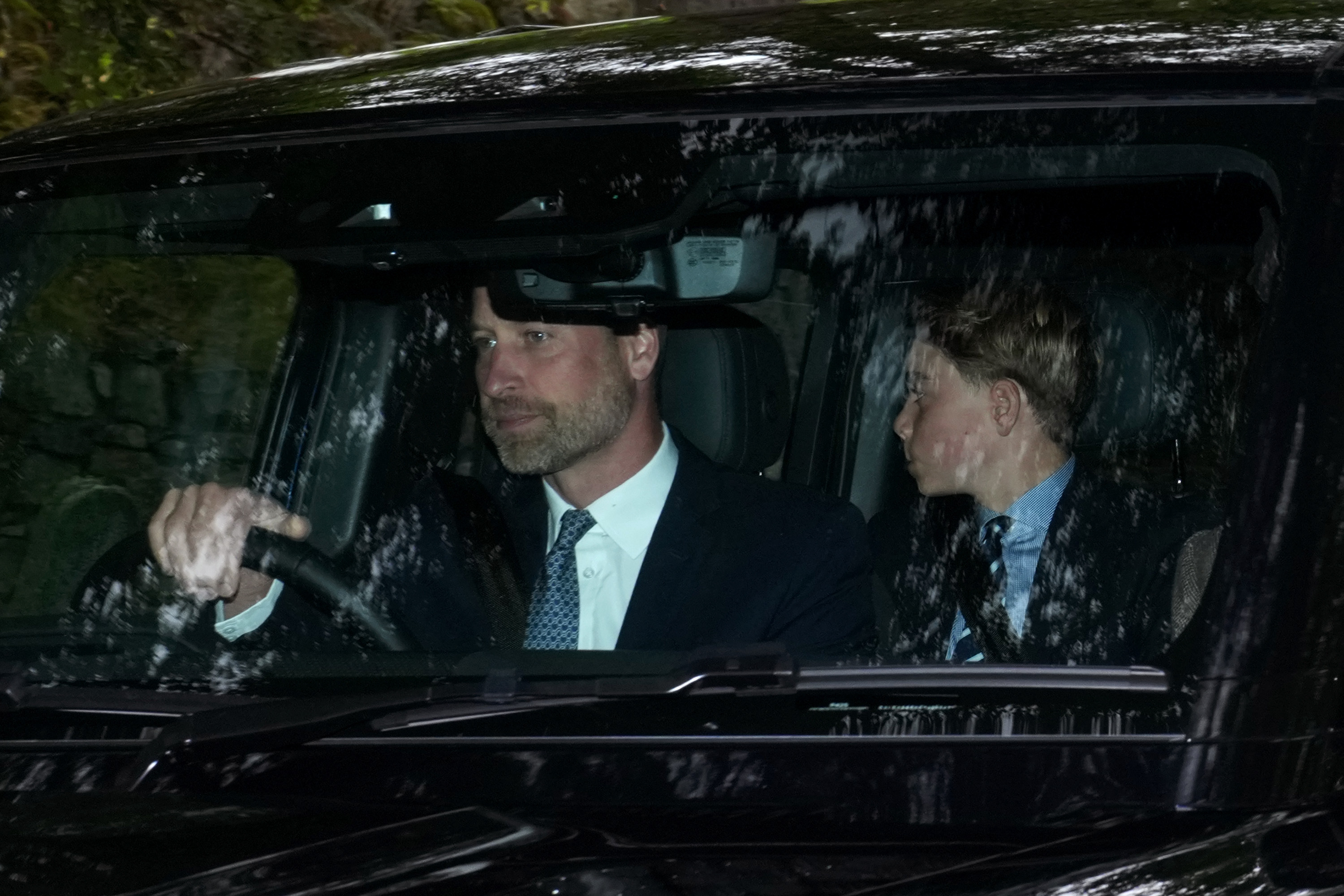 Prince William driving a car with Prince George in the back