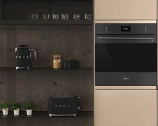 A dark kitchen with copper finishes and black Smeg accessories