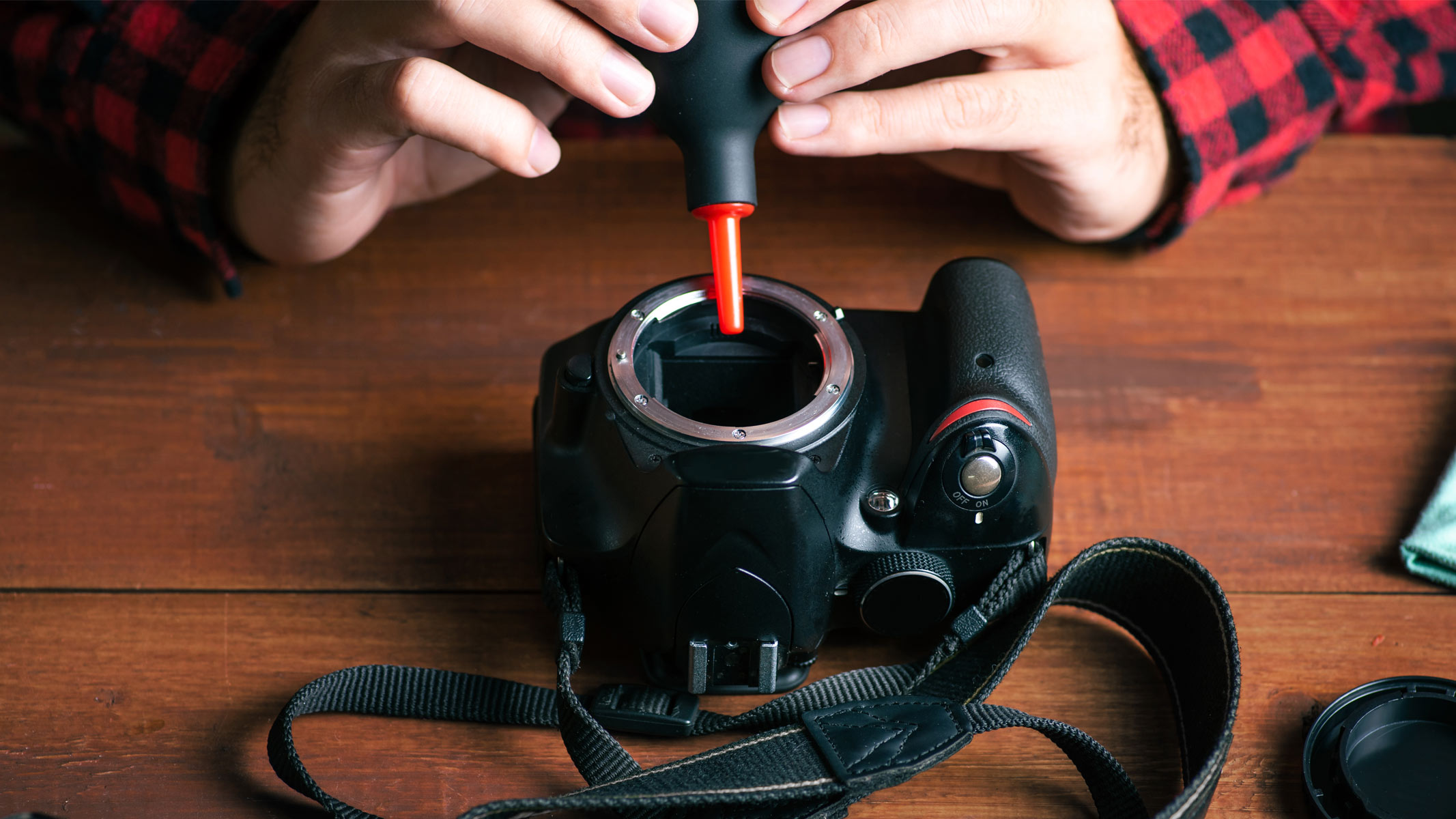 A person using an air puffer to clean a camera sensor.