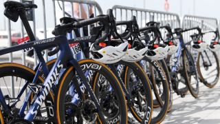 A row of blue race bikes leant up against a metal fence