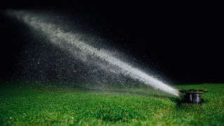 A sprinkler system watering a lawn at night