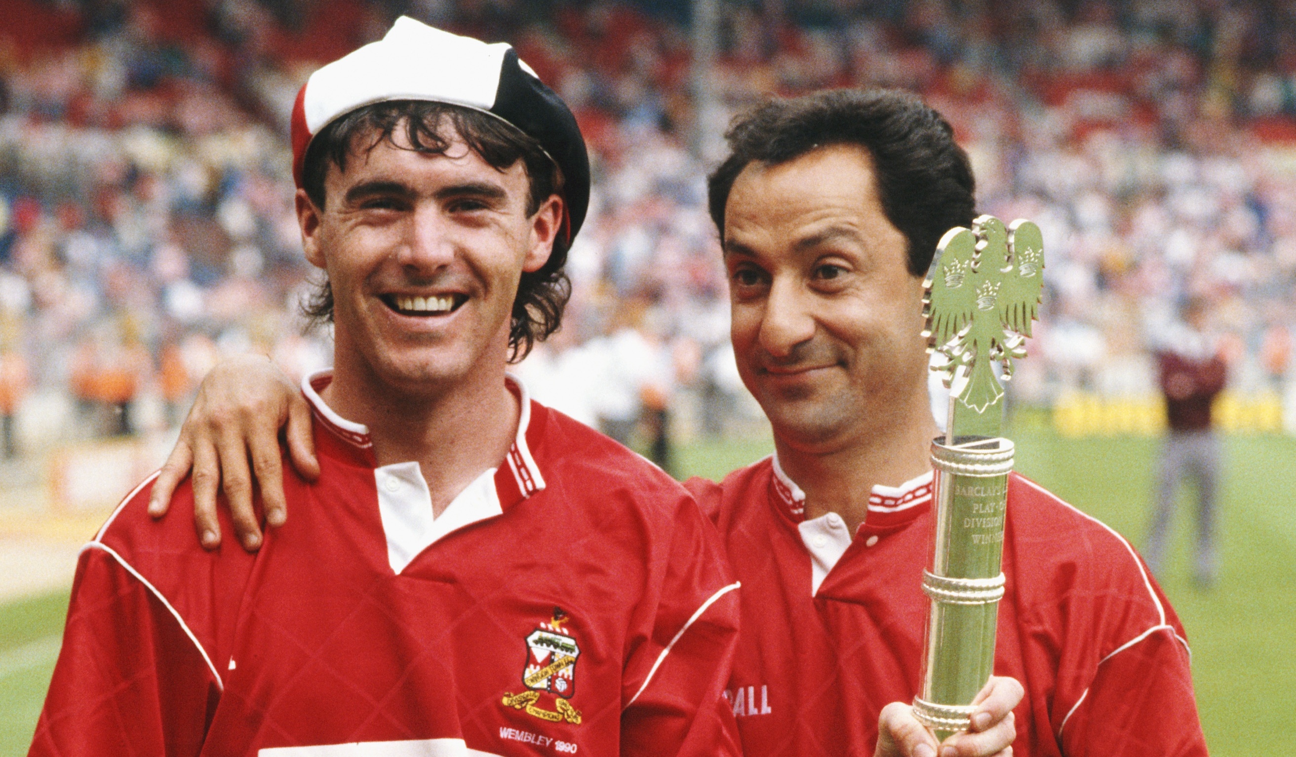 Swindon Town manager Osvaldo Ardiles (r) and player Alan McLoughlin pose with the Division Two play off winners trophy after the Play off Final against Sunderland at Wembley Stadium on May 28, 1990.