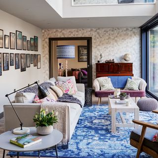 a living room with cream printed wall and blue carpet flooring and cream sofa