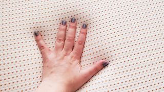 A woman wearing silver nail polish places her hand on the top of the Nectar Premier Copper Mattress to feel how cool it is