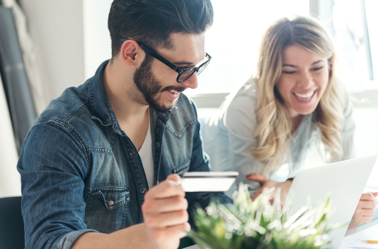 A happy young couple relaxing together and making some online purchases.