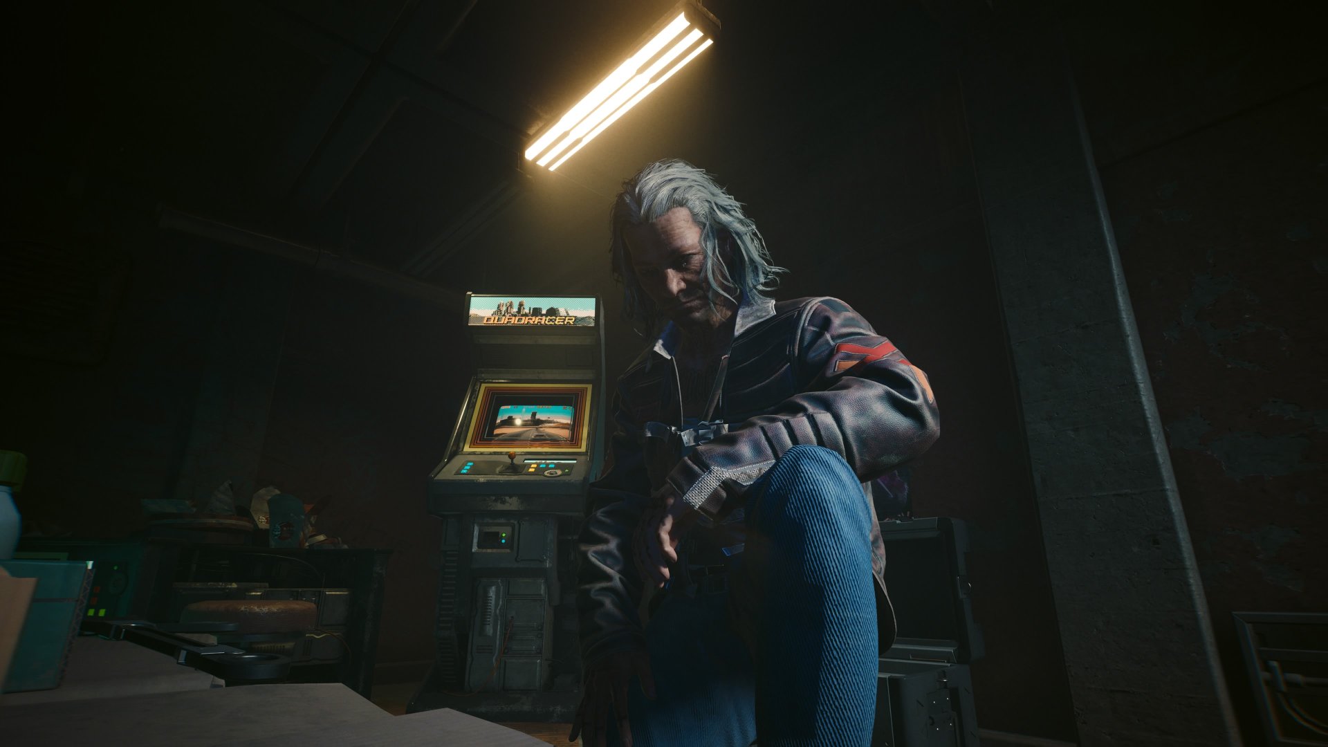 Cyberpunk 2077 Phantom Liberty screenshot of an older man with shoulder length hair called Michael Maldonado who crouches before an arcade machine during the gig Heaviest of Hearts