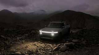 A Rivian R1T electric truck lights up the dark with its long horizontal light bar