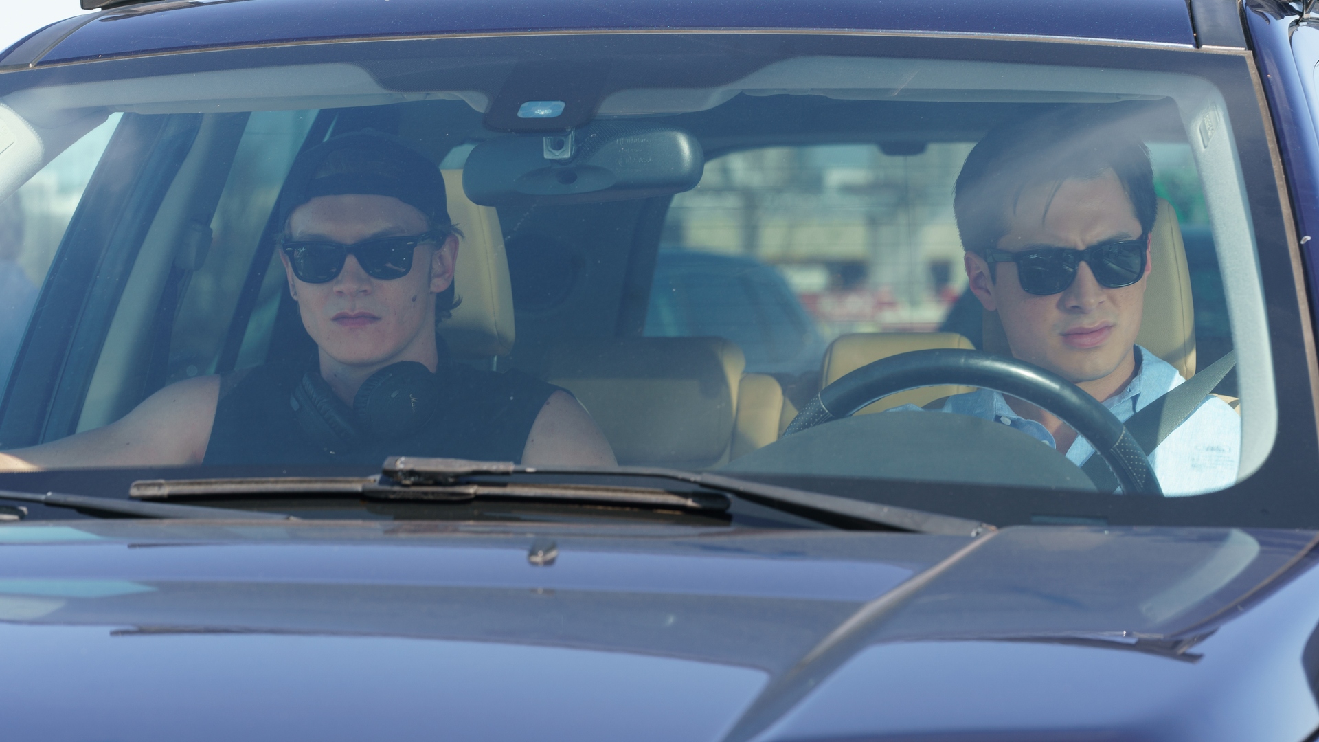 Ilya and Shane drive in a car with sunglasses on in Heated Rivalry