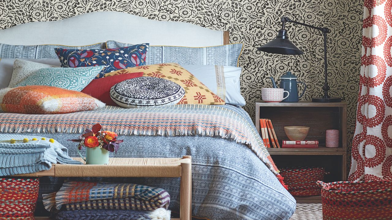 bedroom with bed and colourful bedding with lots of cushions