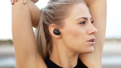 Bose Sport Earbuds review: Young woman wearing the Bose buds looking away from the camera