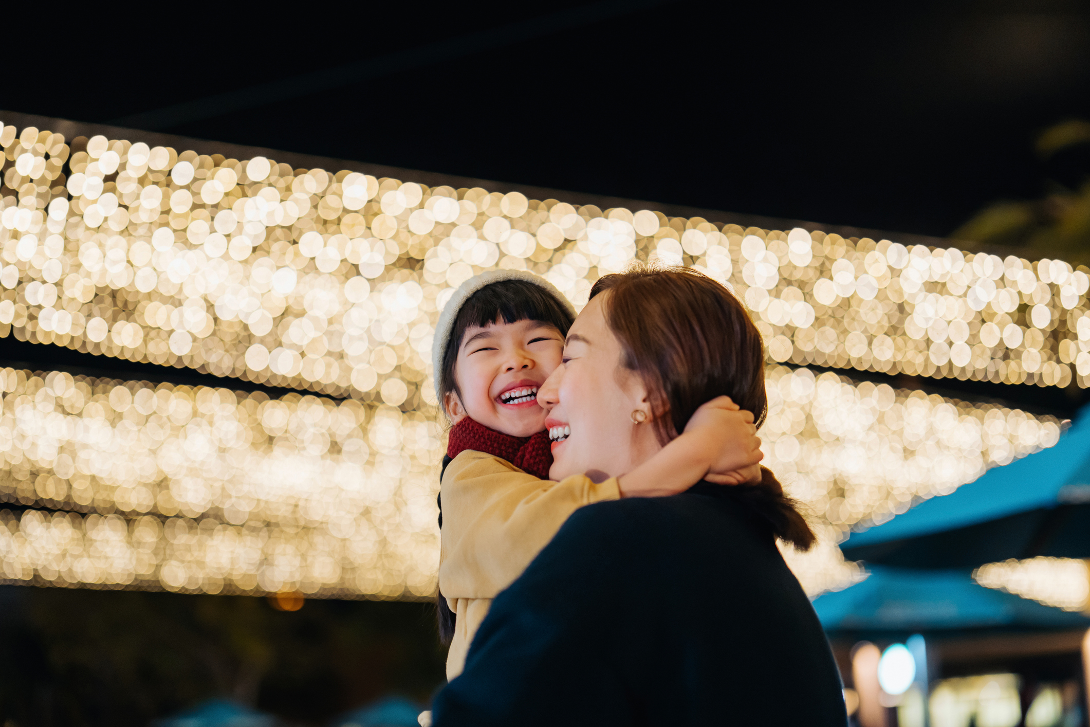 a mom holding her daughter while gazing at Christmas lights