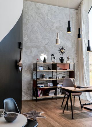 home office with marble wall, open shelving unit, pendant lights, desk, chair, wooden floor, table in foreground