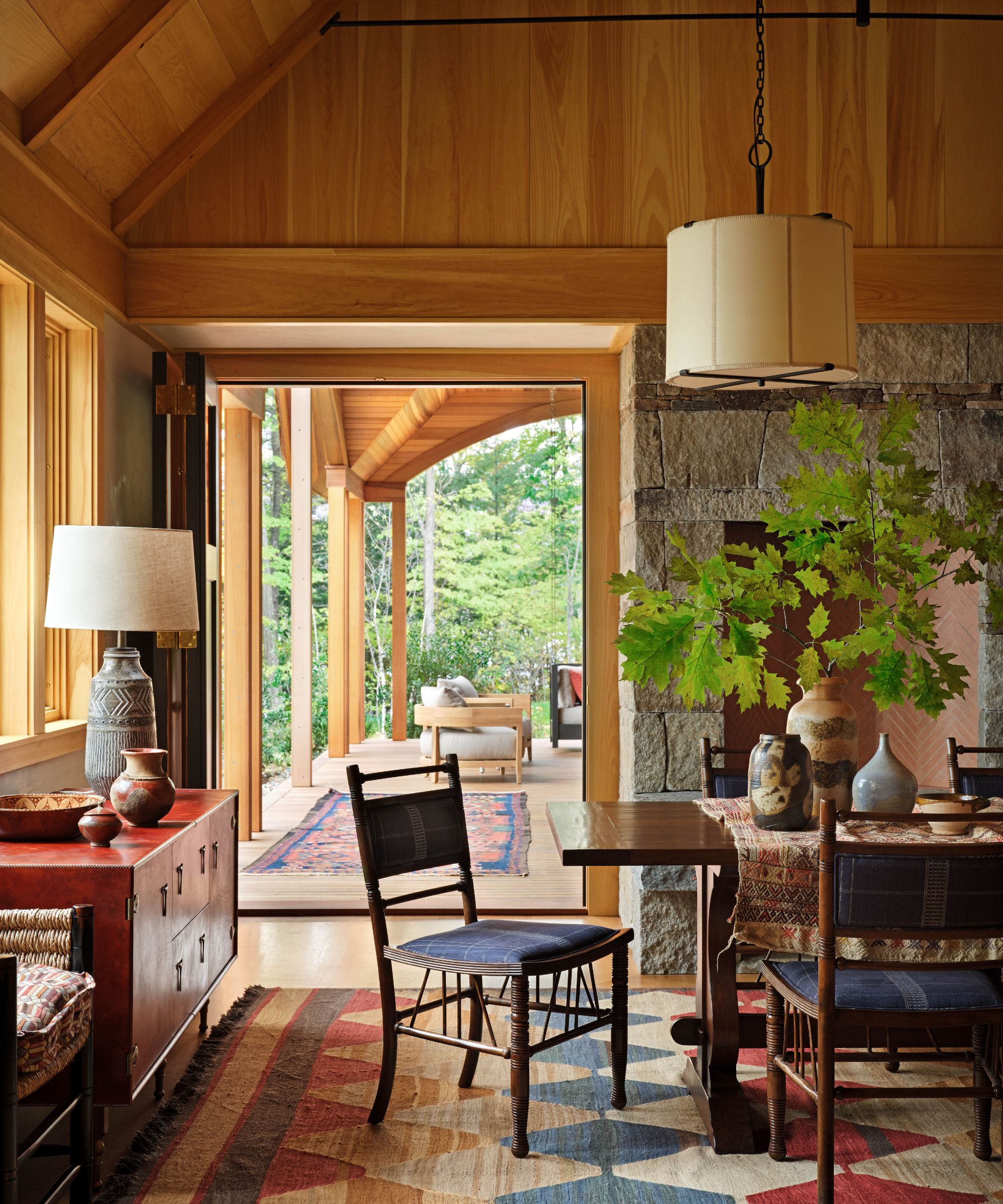 Dining room of wooden panelled cabin with dark wooden dining table, red and blue rug and blue chairs