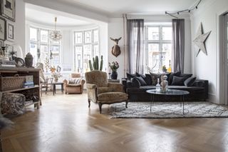 a Danish apartment sitting room with wood chevron flooring and period features